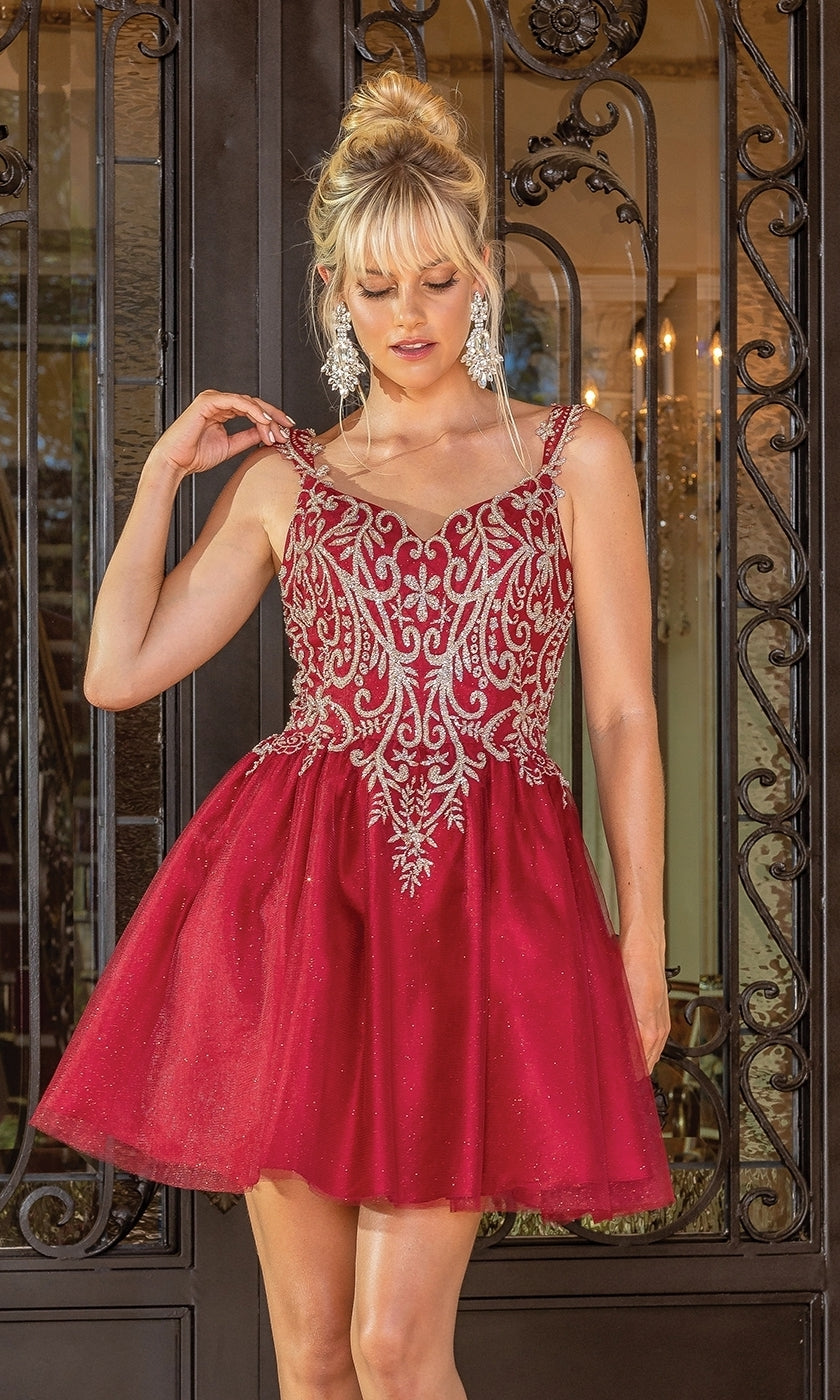 A woman wearing the Embroidered-Bodice Short Glitter Hoco Dress 3295, a red sleeveless party dress with silver embroidery, stands before ornate black doors.